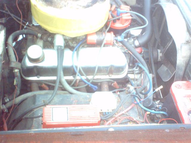 Engine bay with V8 engine, yellow air filter, and red ignition box