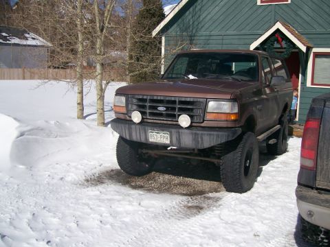1993 Ford Bronco - Brown 1993 Ford Bronco parked in snow with a house in the background.