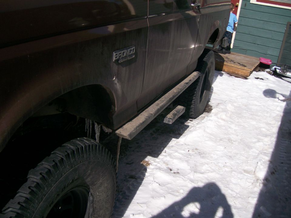 Muddy dark brown Ford Bronco side view on snow with rocker rock slider and BRONCO badge