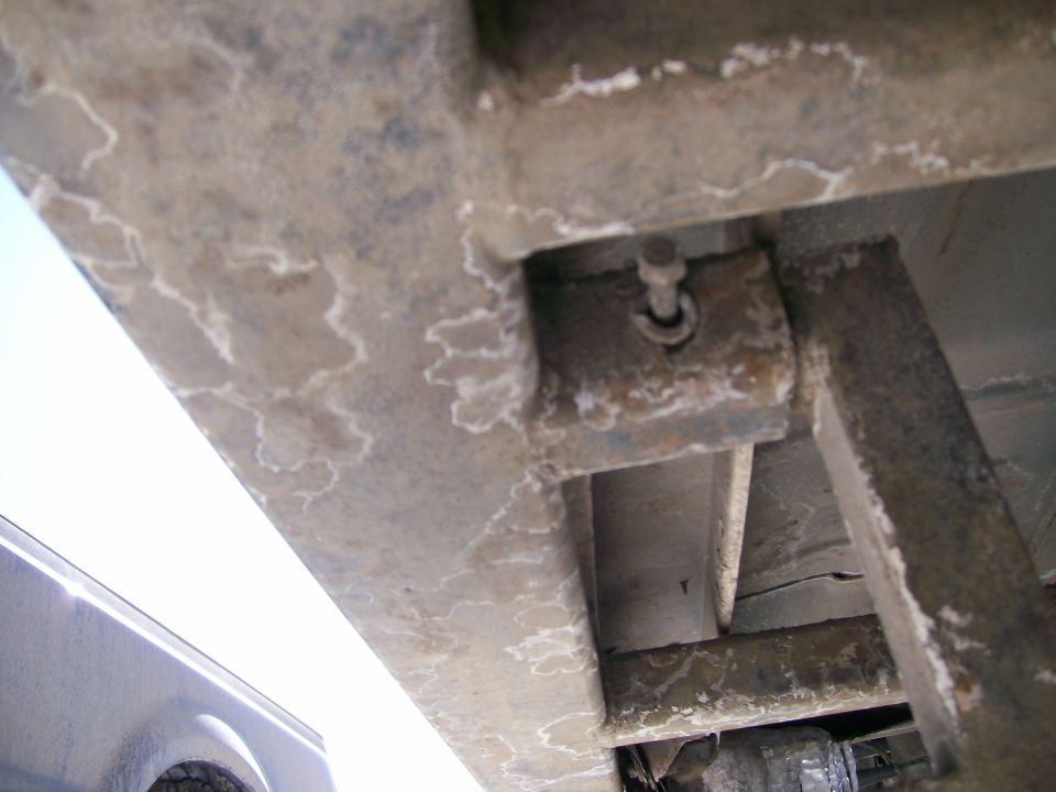 Salt-crusted truck frame rail with body-mount bolt and welded tube brace from below