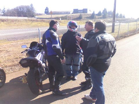 2008 Kawasaki Ninja R - A group of motorcyclists gather around a parked motorcycle on a sunny day.