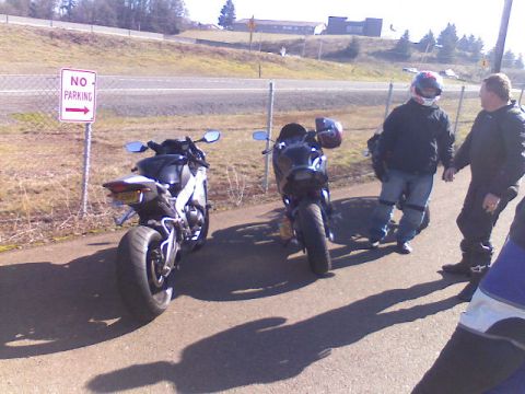 2008 Kawasaki Ninja R - Two motorcycles are parked on a paved area next to a fence, with a 'No Parking' sign visible.
