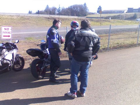 2008 Kawasaki Ninja R - Three people stand next to two motorcycles on a paved area with a 'NO PARKING' sign.