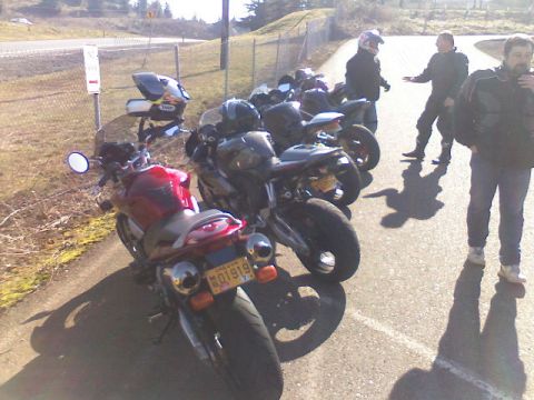 2008 Kawasaki Ninja R - Several motorcycles are parked in a line with people standing nearby.