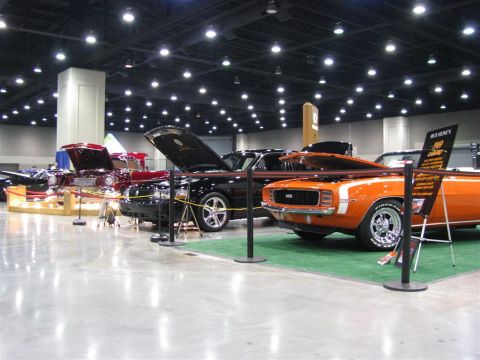 2003 Mercury Marauder - Various custom vehicles are on display at an indoor auto show, with spotlights illuminating the scene.