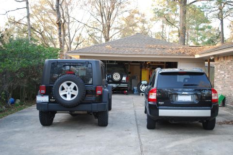 2008 Jeep Wrangler - Two Jeep SUVs are parked in a driveway in front of a garage, one is a Wrangler and the other is a Compass.