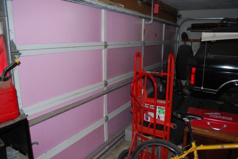 2008 Jeep Wrangler - A black SUV is parked in a garage, partially obscured by a red dolly and a bicycle.