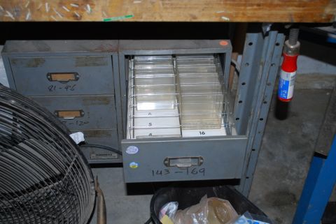 2008 Jeep Wrangler - Gray steel Numberdex index-card cabinets sit on a concrete garage floor under a wooden workbench, one drawer pulled open to show rows of di…