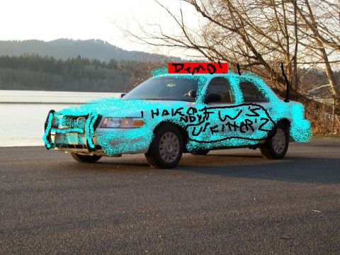 1996 Ford Crown Victoria - A light blue sedan, possibly a Ford Crown Victoria, is parked near a body of water with graffiti on its side.