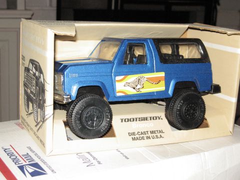 1986 Ford Bronco - A blue die-cast metal Bronco toy by TootsieToy is displayed inside its original packaging.