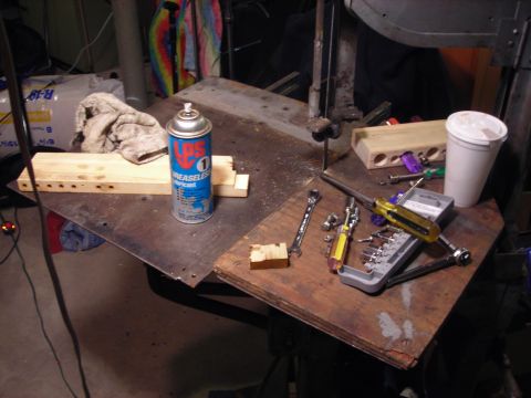 1995 Ford Bronco - A workbench is cluttered with tools and a can of lubricant, suggesting a work-in-progress or repair area.