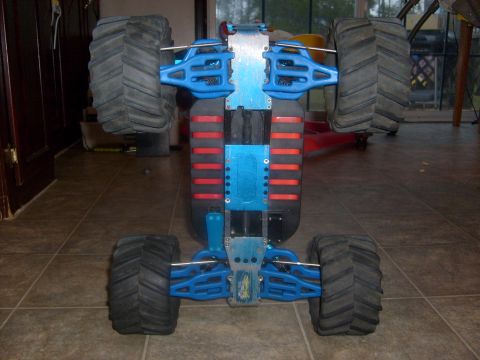 1989 Ford Bronco - Underside view of a blue remote control monster truck chassis, its suspension and large off-road tires.