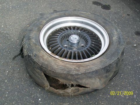 1972 Ford Ranchero - A severely damaged tire and rim lie on asphalt, with a timestamp indicating it was photographed on 02/21/2009.