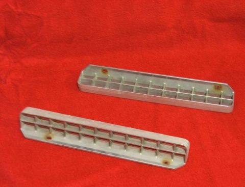 1989 Ford Bronco II - Two aluminum vent grilles are displayed on a red surface.