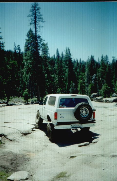 1996 Ford Bronco - White 1996 Ford Bronco parked off-road with a spare tire mounted on the rear.