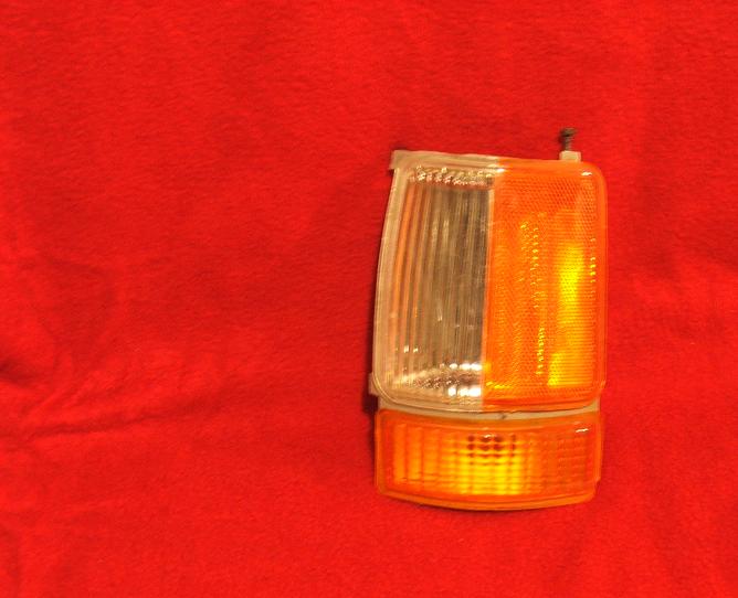 clear and amber plastic vehicle turn signal assembly on red background