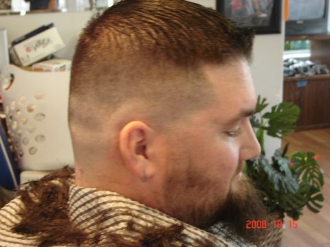 1993 Ford Bronco - A man is shown from the side with a freshly cut high and tight hairstyle and a beard, wearing a barber's cape.