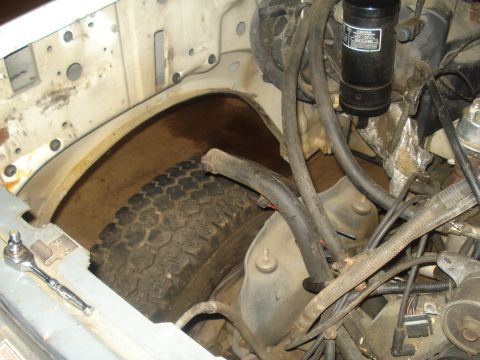 1991 Ford Bronco - A view of the engine bay of a 1991 Ford Bronco, showing the tire well, engine components, hoses, and wiring.