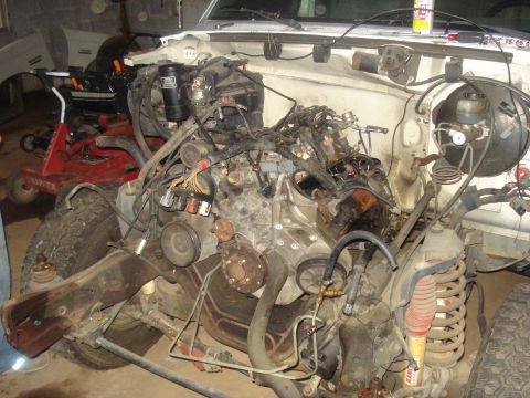 1991 Ford Bronco - The engine bay of a 1991 Ford Bronco is shown with the engine partially disassembled. Various hoses, wires, and engine components are visib…