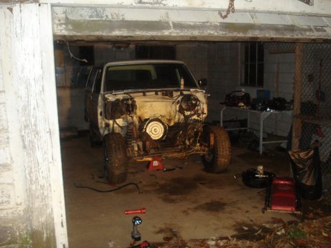 1991 Ford Bronco - A disassembled 1991 Ford Bronco is parked inside a garage with its engine exposed. The vehicle is on jack stands, and various tools and par…