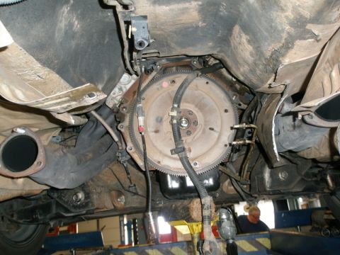 2007 Ford Mustang - Photograph of the underside of a vehicle on a lift showing the flexplate and transmission bellhousing, not a document.