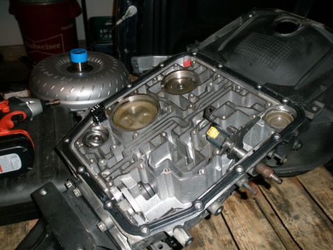 2007 Ford Mustang - Photograph of an open automatic transmission case and torque converter on a wooden workbench, not a document.