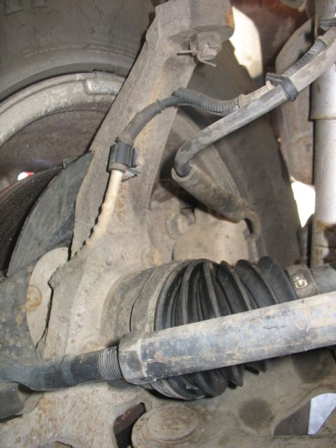 2007 Ford Mustang - Photograph of a vehicle front suspension showing CV axle boot, brake hose and steering knuckle, not a document.