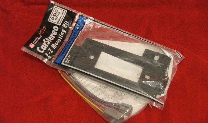 Car stereo mounting kit in packaging on red surface