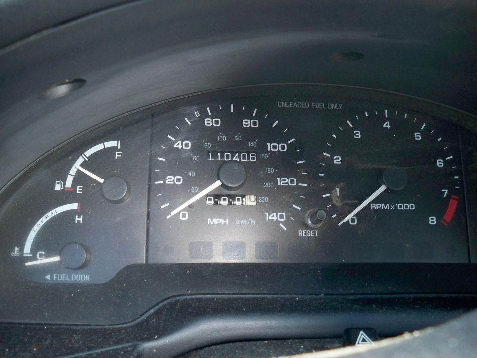 Close-up of a 1995 Ford Probe dashboard with speedometer, tachometer, fuel, and temperature gauges.