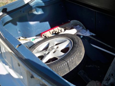 1995 Ford Probe - The trunk of a vehicle is shown with a spare tire, a red taillight assembly, and a white towel. The interior of the trunk is lined with blu…