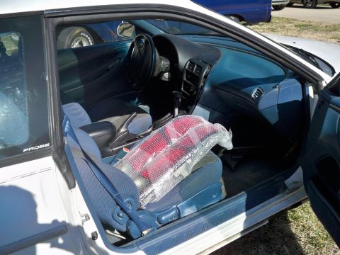 1995 Ford Probe - Interior view of a white 1995 Ford Probe, showing the driver's side door open. The car's blue interior includes seats, dashboard, and a cen…