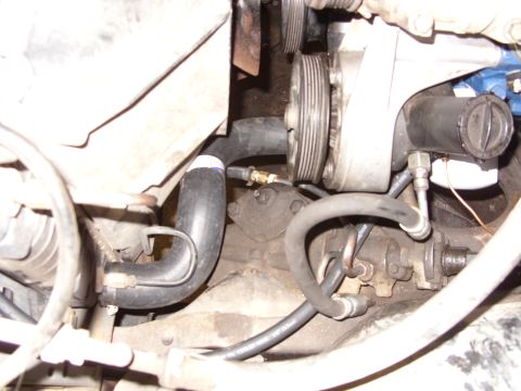 1988 Ford Bronco - This is a close-up, angled view of the engine bay of a 1988 Ford Bronco, focusing on the power steering pump and various hoses. The engine…