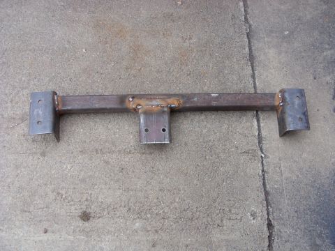 1988 Ford Bronco - A fabricated steel crossmember with mounting brackets and holes is shown lying on a concrete surface. The crossmember appears to be a custo…