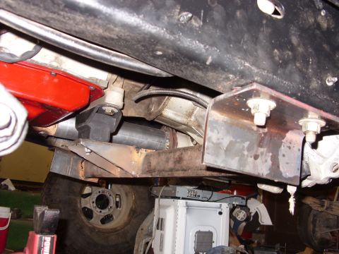 1988 Ford Bronco - Underside close-up of a fabricated bare-steel skid plate and crossmember bolted to the frame rails with large hex bolts, protecting a rear-…