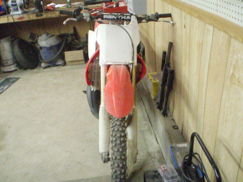 Red and white dirt bike front view, handlebars visible, knobby tire