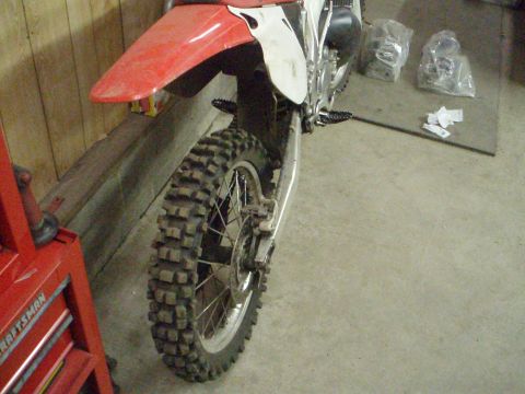 2005 Honda CR125R - Rear view of a dirt bike, showing the knobby tire and red fender, with a red Craftsman tool chest to the left.