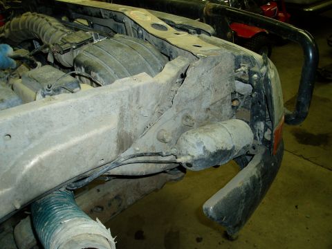 2000 Ford E350 - The front passenger side of a heavily soiled 2000 Ford E350 van is shown, with the fender, bumper, and engine components visible. The vehic…