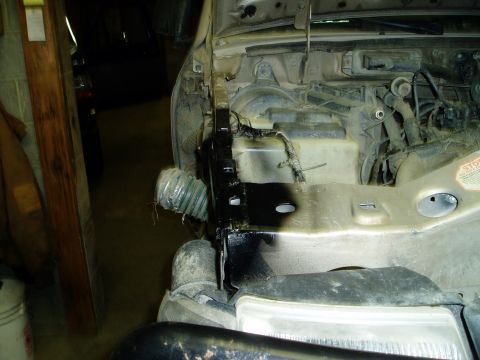 2000 Ford E350 - Close-up view of the engine bay of a 2000 Ford E350, showing the battery tray area and some wiring. A flexible hose is visible near the fro…