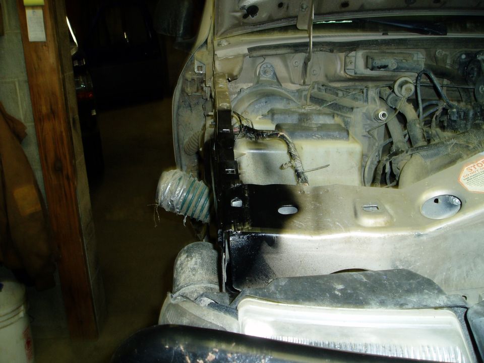 2000 Ford E350 engine bay, showing battery area, wiring, and flexible hose.