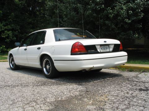 1998 Ford Crown Victoria - Rear view of a white 1998 Ford Crown Victoria, showing its distinctive taillights and license plate.