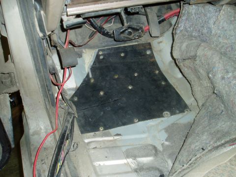 2000 Ford E350 - This image shows the interior floor area of a vehicle, likely a van, with a custom black plate installed over the transmission tunnel. Vari…