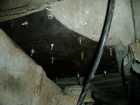 2000 Ford E350 - A custom metal plate is bolted to the underside of a vehicle frame, likely reinforcing or modifying a suspension component. Several bolts w…