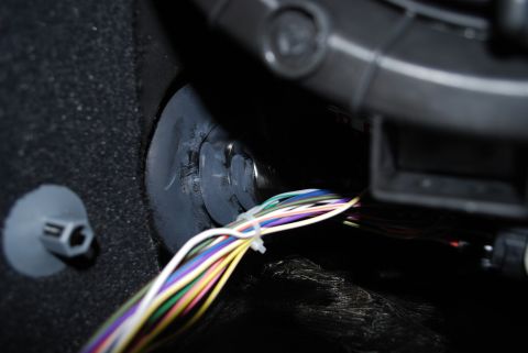 2008 Jeep Wrangler - A bundle of colorful wires is secured with a zip tie and passes through a rubber grommet in a dark, textured surface. A grey plastic fasten…
