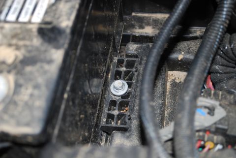 2008 Jeep Wrangler - A close-up view shows a silver bolt securing a black plastic bracket within a vehicle's engine bay. The surrounding area is dusty and inclu…