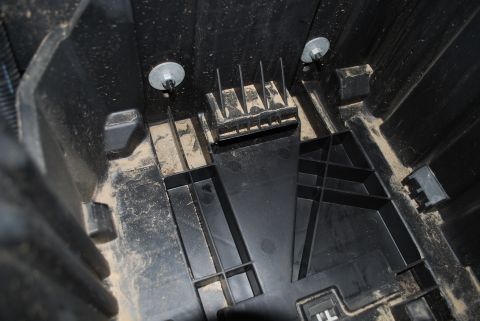 2008 Jeep Wrangler - A close-up view shows the interior of a black plastic storage compartment, likely for a battery or tool kit, with two silver bolts securing…