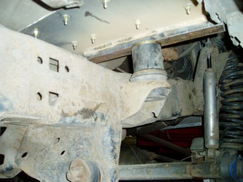 2000 Ford E350 - Underneath view of the front suspension and frame of a 2000 Ford E350, showing a modified suspension system with a large rubber bushing and…