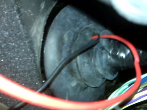 2008 Jeep Wrangler - A close-up view shows a black rubber grommet with a red wire passing through it, surrounded by a textured surface and other wires. This app…
