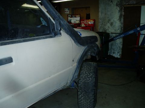 2000 Ford E350 - The side view of a light-colored vehicle, possibly a van or SUV, is shown in a garage setting. A snorkel intake is visible on the front fen…