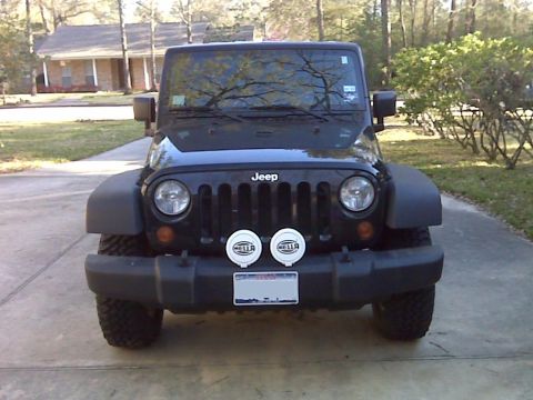 2008 Jeep Wrangler - Front view of a black Jeep Wrangler parked on a concrete driveway in front of a house. The vehicle has aftermarket fog lights mounted on th…