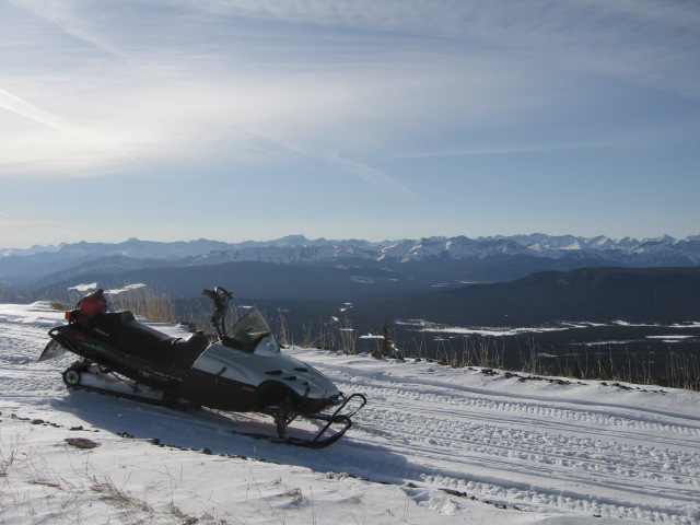 1999 Arctic Cat Powder Special 600 EFI snowmobile parked on a snowy ridge with mountains in the background.